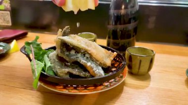 Yeşillik ve içecekle servis edilen lezzetli kızarmış balıklar.