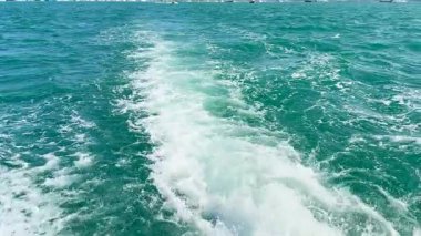 Bir tekne Phuket, Tayland yakınlarındaki turkuaz sularda, berrak gökyüzünün altında, dinamik bir uyanış yaratır.