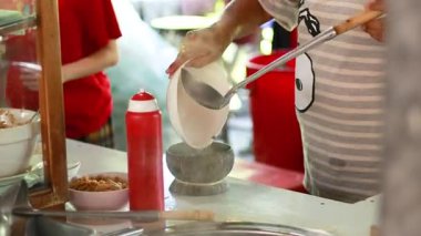 Satıcı hindistan cevizi kabuklu şehriye çorbası servis ediyor.