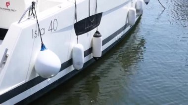 Rıhtımdaki bir teknenin yanında yüzen çamurluklar.