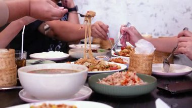 Bir masada yemek paylaşan arkadaşlar.