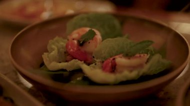 Tahta bir tabakta karides miang kham tabağının yakın çekimi, sıcak, ortam aydınlatması ile yakalanır.