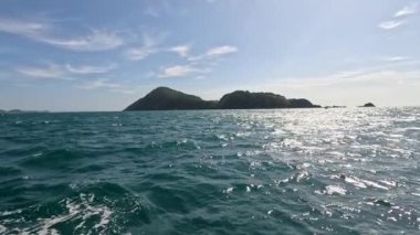 Phuket kıyılarında canlı bir balık avı, açık gökyüzü, mavi sular, ve renkli bir teknede odaklanmış bir balıkçı