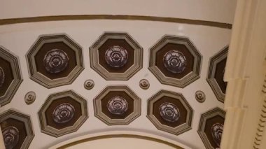 Süslü tavanı ve park edilmiş arabaları olan bir avlu.