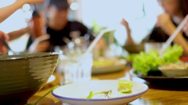 Canlı bir grup, Bangkok 'ta hareketli bir masada hareketli etkileşimler ve canlı ışıklandırmayla Vietnam mutfağından zevk alıyor.