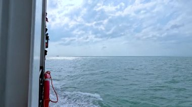 Sakin bir feribot yolculuğu bulutlu bir gökyüzünün altında Koh Samui 'nin sularının sakinliğini ön plana çıkaran engin okyanusu yakalar.