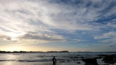 Dalgalar ve insanlar gün batımı sahnesinde