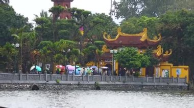 Tapınak girişinde şemsiyeli insanlar var.