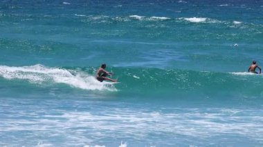 Sörfçüler dalgaları sırayla yakalayıp sürüyorlar.