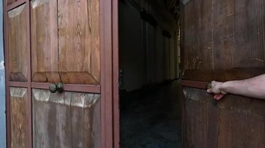 Bir el, ahşap kapıyı açar ve kapatır.