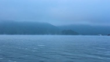 Uzak dağlarla sisli nehir manzarası