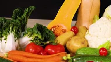 Koyu bir zemin üzerinde çeşitli sebzeler sergilenir