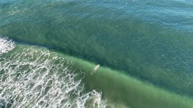 İnsansız hava aracı Gold Coast 'ta sörf yapan dalgaları yakalıyor. Açık gökyüzü, canlı okyanus, dinamik hareket