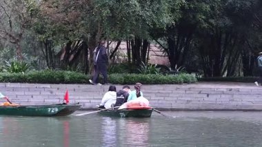 İnsanlar Ninh Binh 'de nehir kenarında kürek çekiyorlar.