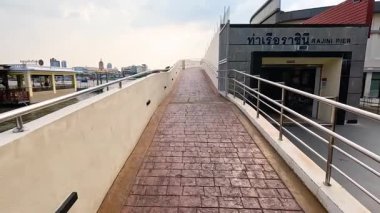 Bangkok, Tayland 'da nehir kenarındaki bir rıhtımda doğal gün ışığı altında kentsel mimari ve nehir manzaralarını gösteren manzaralı bir yürüyüş.
