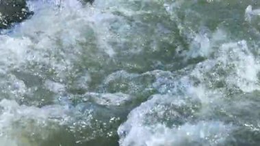 Wakatipu Gölü 'ndeki çalkantılı suyun yakın çekim videosu, parlak ışık altında doğal hareketleri ve dinamik dokuları gösteriyor.