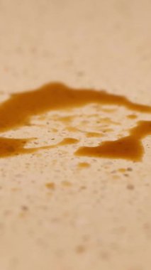 Bir insan sıcak ışık altında mavi bir bez kullanarak benekli bir tezgahın üzerine kahve döker.