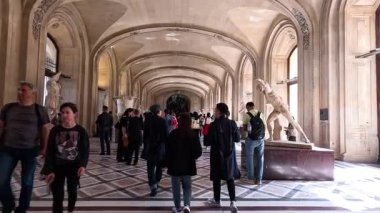 Louvre 'da bir koridorda yürüyen insanlar.