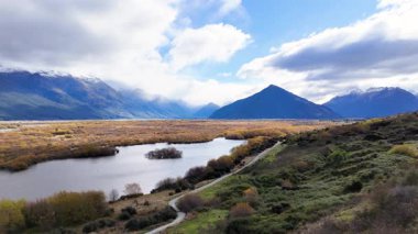 Glenorchy 'nin bulutlu bir gökyüzünün altında göl, dağlar ve yemyeşil bir hava manzarası.
