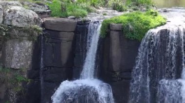 Çağlayarak akan şelale yeşillik ile kayalık uçurumun üzerinde