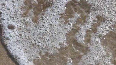 Dalgalar yavaşça kumlu sahilde süzülüyor