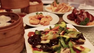 Çeşit çeşit Çin yemekleri ve dönen cam bir sehpanın üzerinde, sıcak bir ışıkla yakalanmış.