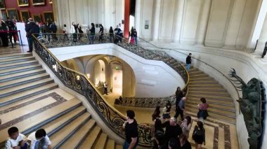 Görkemli bir merdivenden inip çıkan ziyaretçiler.