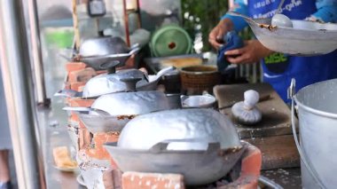 Tedarikçiler Tayland 'ın Phuket şehrinde metal kalıplar kullanarak geleneksel Tayland hindistan cevizi atıştırmalıkları hazırlıyorlar. Parlak, doğal ışıklandırma sahneyi güçlendirir.
