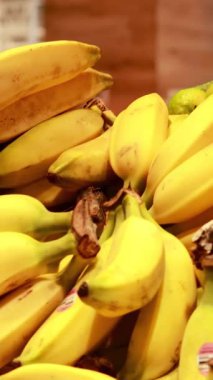 İyi aydınlatılmış bir süpermarket ortamında taze muzların yakın çekimi, tazeliği ve bolluğu vurguluyor