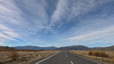 Sonbahar boyunca, Tekapo Gölü, Yeni Zelanda 'da geniş gökyüzü ve uzak dağlarla dolu bir otoyol boyunca sakin bir yolculuk.