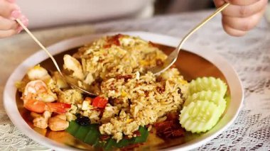 Karides ve sebzeli ananas pilavı servis eden eller.