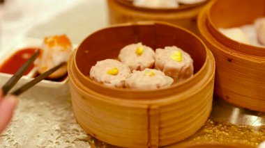 Çubuklar, Çin lokantasında sıcak aydınlatılmış bir bambu buharlı buharlı tencereden Çin yemeği topluyor.