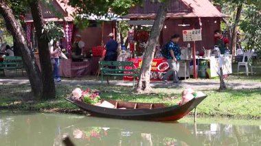Bangkok parkındaki bir teknenin yanında insanlar etkileşime geçiyor.