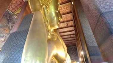 Wat Pho, Bangkok 'taki altın uzanan Buda heykelinin sakin manzarası, karmaşık tapınak ayrıntılarını ve ortam aydınlatmasını sergiliyor.