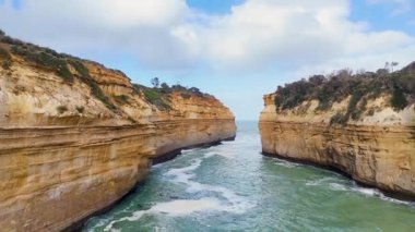 İnsansız hava aracı görüntüleri, parlak gün ışığında Avustralya 'nın Port Campbell kentindeki Loch Ard Gorge' daki engebeli kayalıkları ve çalkantılı okyanusu yakalar.