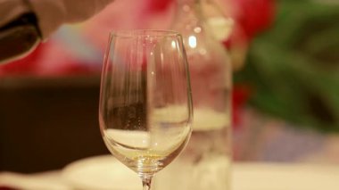 Bir kadehe dökülen kırmızı şarap dizisi, yumuşak ışıklandırmayla güzel bir yemeğin zarafetini vurguluyor.