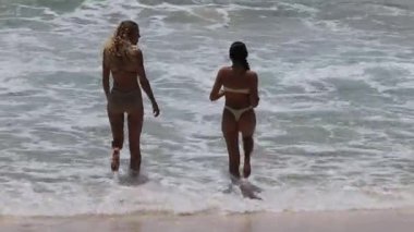 İki kadın birlikte okyanusa giriyor.