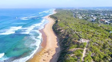 Hava görüntüleri, açık gökyüzü altında canlı okyanus dalgaları ve yemyeşil yeşilliklerle Point Lonsdale, Avustralya 'nın manzaralı sahil şeridini yakalar.