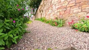 Canlı çiçeklerle dolu manzaralı taş bir patika.