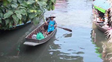 Bir tekne Bangkok pazarında bir kanalda geziniyor.
