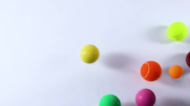 Beyaz arkaplan boyunca hareket eden çeşitli toplar