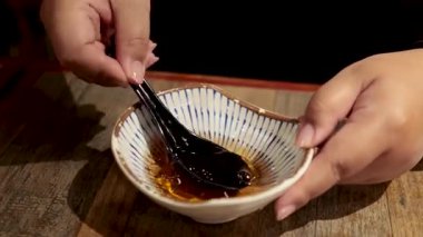 Eller siyah kaşıkla sos karıştırıyor.