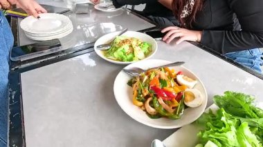 Canlı Laos yemekleriyle dolu bir masa seti, taze sebzeler ve ızgara etler dahil, açık hava ortamında.