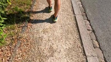 Güneşli bir kaldırım taşı yolunda yürüyen kişi