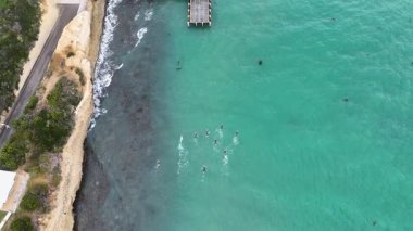 Drone Avustralya, Port Campbell yakınlarındaki turkuaz sularda yüzücüleri yakalar. Açık gökyüzü ve canlı okyanus dinamik bir eğitim sahnesi oluşturur.