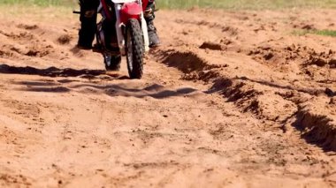 Kumlu bir pistte motosiklet süren bir sürücü.