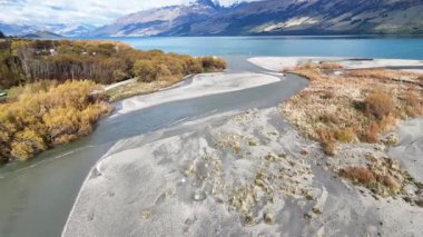 Hava görüntüleri, Glenorchy, Yeni Zelanda 'daki dingin nehir kıvrımlarını canlı sonbahar yaprakları ve berrak gökyüzünün altında görkemli dağlarla yakalar.