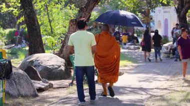 Bir keşiş ve bir adam parkta geziniyor.