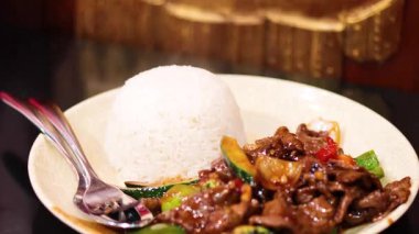 Haşlanmış beyaz pirinçle servis edilen cızırtılı biftek.