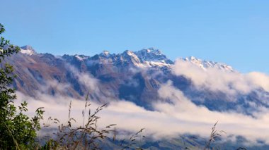 Karla kaplı dağlar ve berrak mavi gökyüzünün altında yumuşak sisle kaplanmış yemyeşil alanlar. Glenorchy, Yeni Zelanda 'da Yakalandı